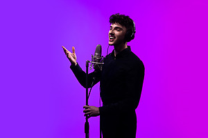 dekoratyvinis asociatyvus paveikslėlis su dainuojančiu vaikinu prie mikrofono