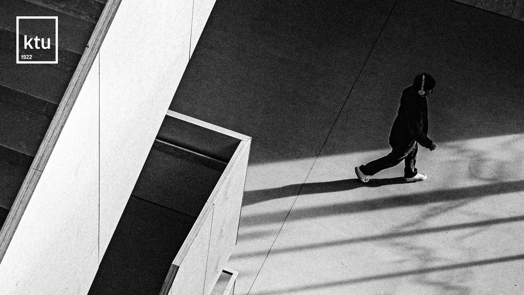 Studijuok dėl savęs – rinkis studijas KTU. Juodai baltoje Remigijaus Ščerbausko fotografijoje – studentas su ausinėmis žingsniuoja per modernų KTU interjerą, šviesa ir šešėliai kuria architektūrinę ritmiką. Kairiajame viršutiniame kampe – šviesus KTU logotipas.