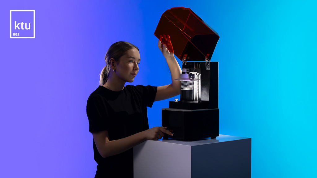 Studijuok dėl savęs – rinkis studijas KTU. KTU dizaino ir inžinerijos kryptys skatina kurti sprendimus, keičiančius realybę. Darbalaukio užsklandoje – studentė atidaro 3D spausdintuvo apsauginį dangtį, aplink – tamsus melsvas fonas ir ryškus raudonas akcentas. Kairiame viršutiniame kampe matomas šviesus KTU logotipas.