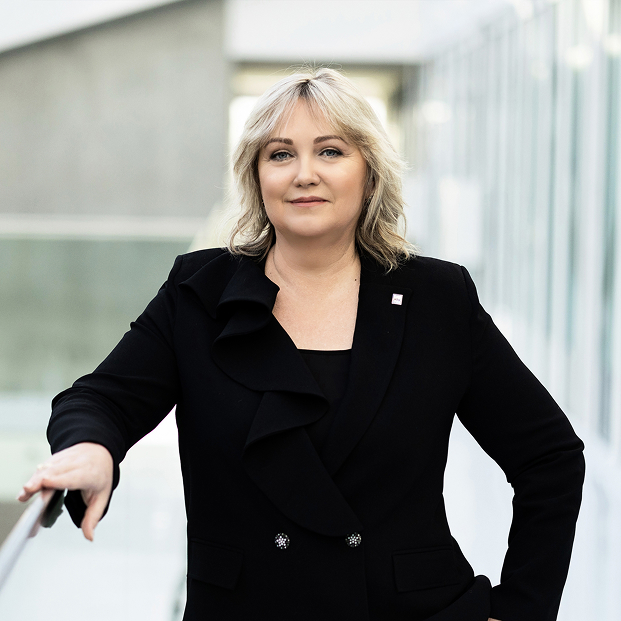KTU bendruomenės reikalų prorektorė doc. dr. Evelina Meilienė KTU bendruomenės reikalų prorektorės portretinė nuotrauka. Moteris šviesiais banguotais plaukais vilki juodą švarką ir stovi atsirėmusi į turėklą. Ji žvelgia į kamerą, o fone matoma šviesi universiteto erdvė.