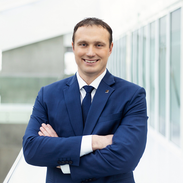 KTU mokslo prorektorius prof. dr. Kęstutis Baltakys KTU mokslo prorektoriaus portretinė nuotrauka. Vyras trumpais tamsiais plaukais vilki mėlyną kostiumą, baltus marškinius ir mėlyną kaklaraištį. Jis stovi sukryžiavęs rankas universiteto koridoriuje ir šypsosi.