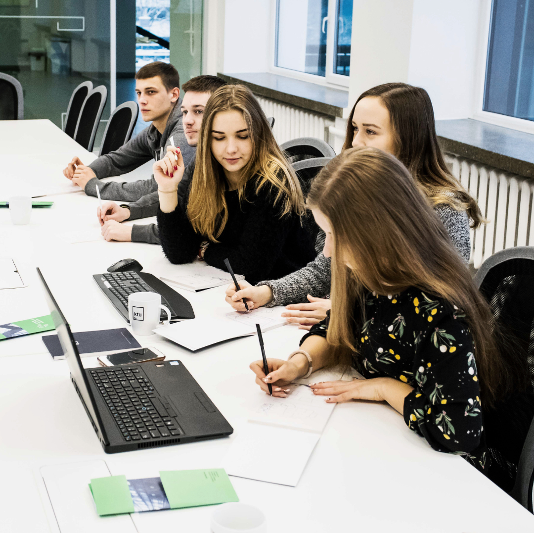 Laukiami rezultatai – Moksliniai tyrimai ir eksperimentinė plėtra technologijų pažanga Studentai ir tyrėjai dirba kartu prie kompiuterių universiteto auditorijoje. Vizualas atspindi mokslu grįstų kompetencijų ugdymą, įsitraukimą į mokslinius tyrimus ir naujos kartos tyrėjų rengimą technologijų pažangai.