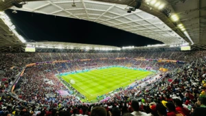 Pilnas futbolo stadionas rungtynių metu – aikštėje žaidžia komandos, o tribūnos užpildytos tūkstančiais sirgalių
